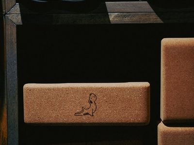 Eco-friendly cork yoga blocks and a rolled blue mat on dark floor